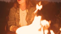Woman Sitting Outside by a Fire at Night
