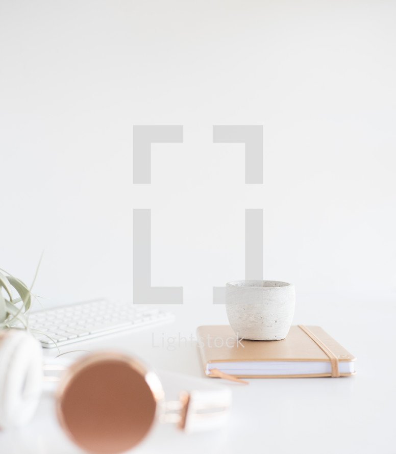 house plant, computer keyboard, journal, candle, headphones, white background, desk, home office, winter 