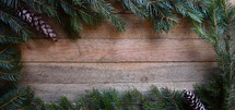 Border of Spruce branches on wooden background with pine cones