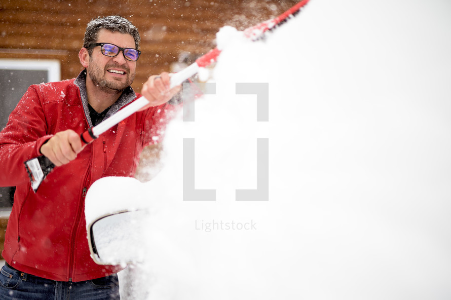 man shoveling snow off a car 