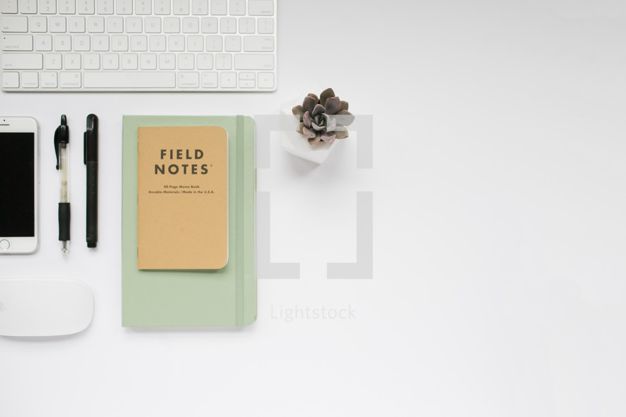 computer keyboard, field notes book, journal, pens, computer mouse, succulent plant, desk, white background