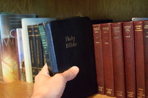 a man taking a Bible off a shelf 