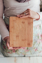 a woman holding up a cutting board 