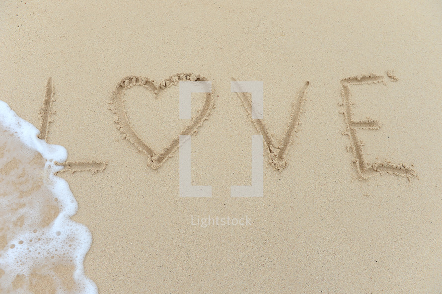 Love written in the sand at the beach.
