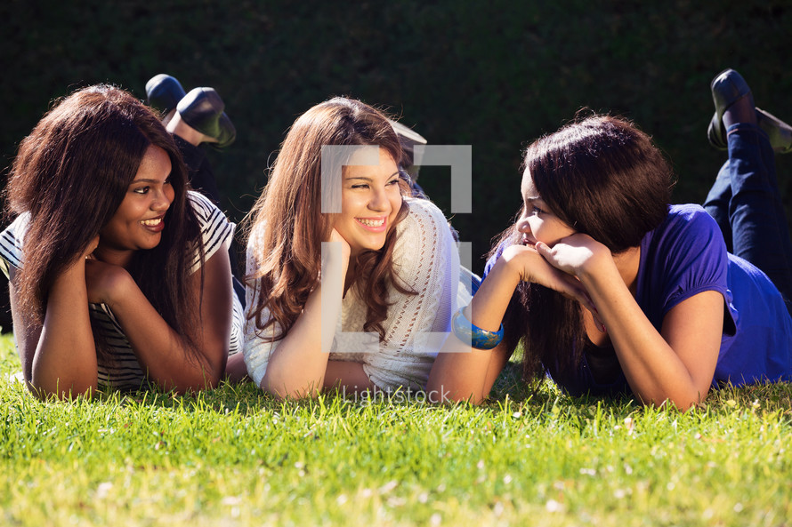 three friend lying in the grass talking 