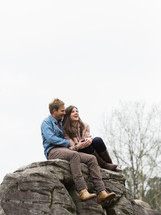 couple hugging sitting on a rock 