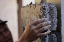 a man setting a brick in mortar 