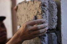 a man setting bricks in mortar 
