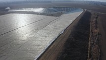 Aerial shot of an agricultural water reservoir surrounded by fields. Irrigation concept
