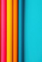 Vibrant, colorful rolls of material aligned vertically against a bright blue background, emphasizing minimalism and modern design.