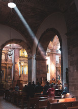 light through skyline shining on a woman in church pews 