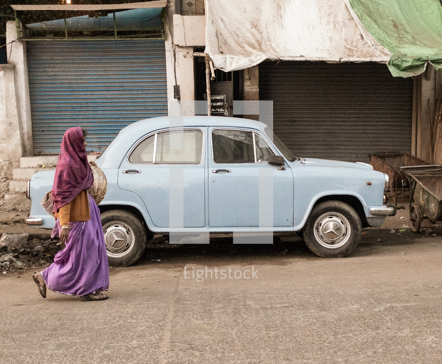 a vailed woman walking past a parked car 