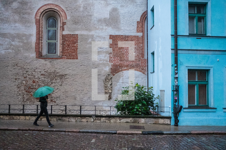 person with an umbrella walking down a sidewalk 