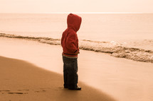 toddler boy standing on a shore 