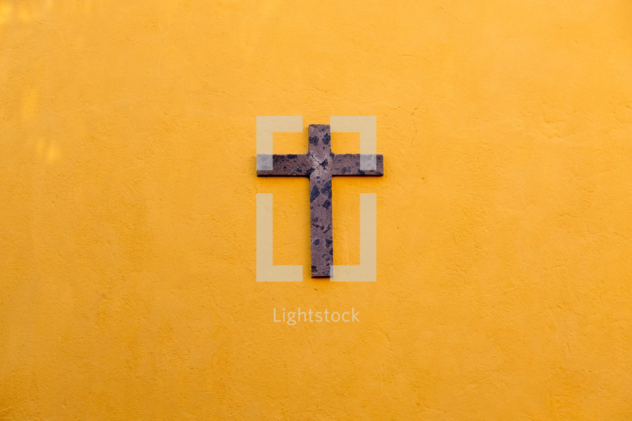 wood cross on a yellow wall 