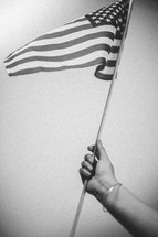 woman's arm holding up an American flag 