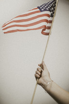 woman's arm holding an American flag 