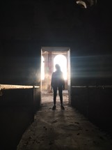 a woman standing in sunlight in an abandoned building 