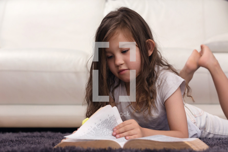 girl reading a Bible on a carpet 