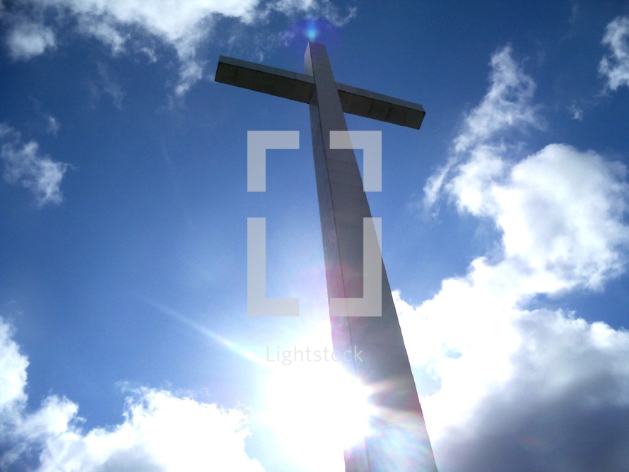 The Reach of the Cross from Heaven to Earth - A Powerful photograph by Artist Rick Short of the Cross reaching above the clouds and sunset reaching from the earth to the Heavens with a sun flare in the background. 