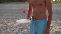 Man Bounces Ball On Beach Paddle