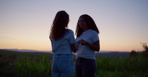 Two girls praying at dusk in a field 3