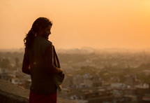 a man standing on a rooftop looking out at a city in India 
