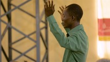 man with hands raised during a worship service in Haiti 