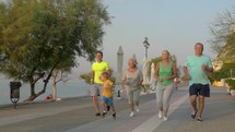 Big family running on road next to the sea