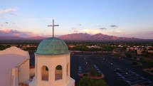 Aerial lift of a church bell tower with cross and scenic mountains