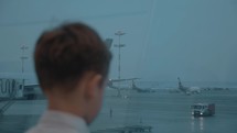 Boy looking at plane in the window when waiting for his flight