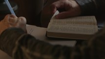 man taking notes reading a Bible 