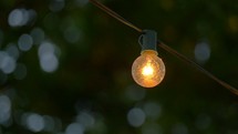 glowing light bulb on a string of lights over an outdoor patio 