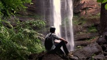 a young man looking at a waterfall 