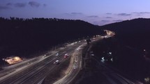 Drone aerial shot of night traffic on a highway showing cars driving and lanes of light with bridges and viaducts