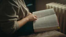 Young woman reading a bible in cozy home environment