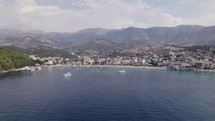 Aerial approaching sandy beach against mountains, Himare, Albania.