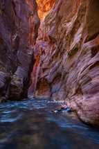 water flowing in a river and red rock cliffs 