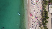 Beachgoers swimming and enjoying white sand beach at Himarë, Albania; aerial
