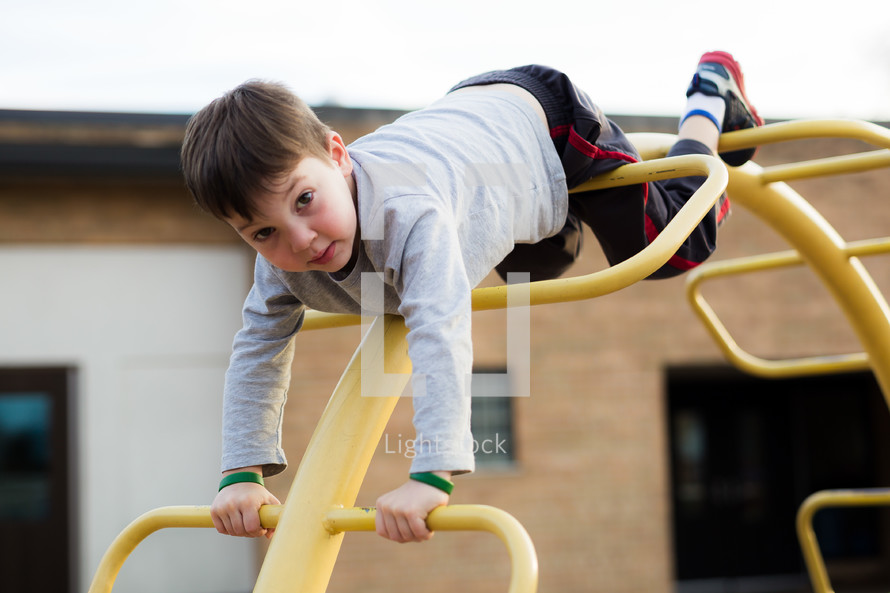 a boy child on a climber on a playground 