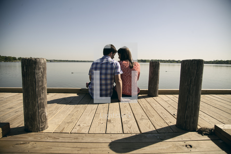 Couple sitting on a pier.