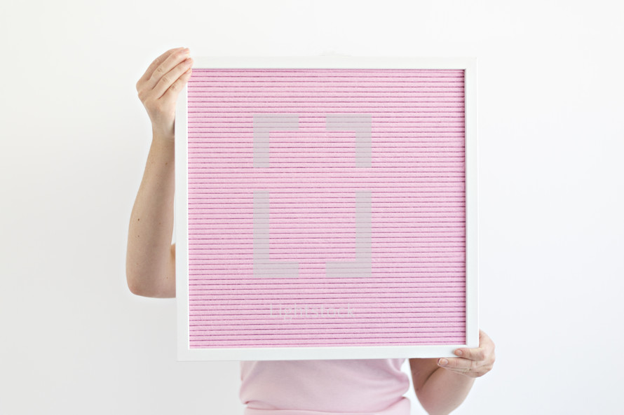 a woman holding a blank pink sign letter board 