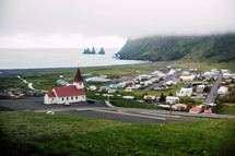 red roof church and homes along a shore in Iceland 