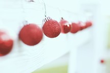 red Christmas ornament balls hanging on a white mantel 