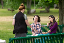 Woman handing gospel tract to people on park bench