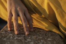 woman's hand touching concrete and fabric of her dress