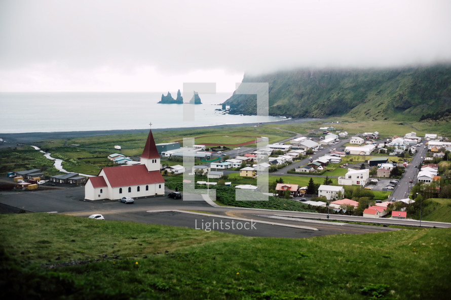 red roof church and homes along a shore in Iceland 