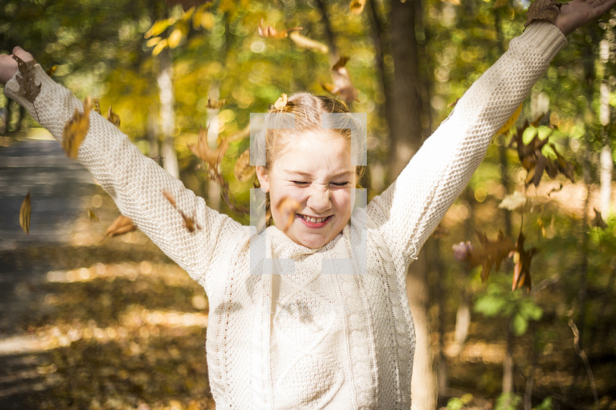 a girl tossing fall leaves in the air 