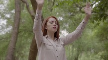a woman with raised hands standing outdoors 
