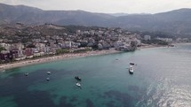 Aerial of boats calmly resting on the azure bay of Himara, Albania
